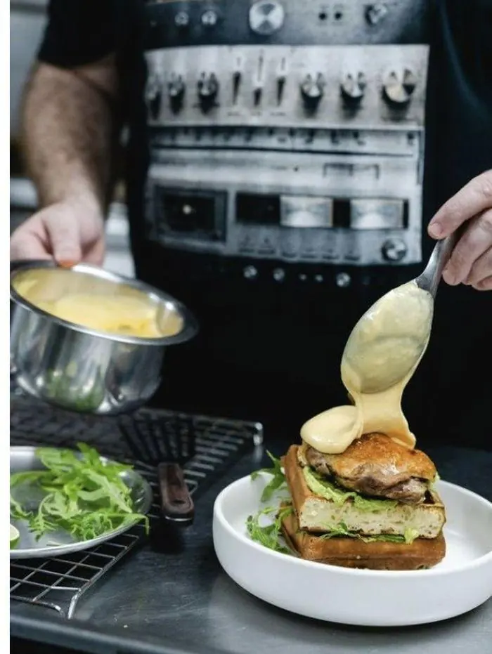 Sauce being poured over a toasted sandwich at Melbourne café