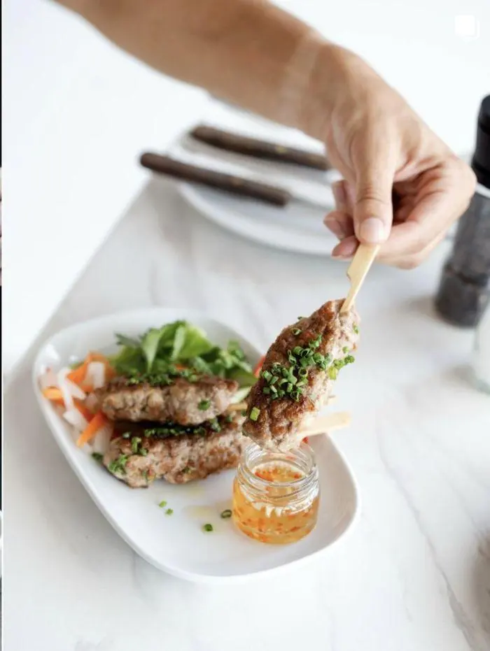Skewers plated with herbs and dipping sauce at Melbourne café